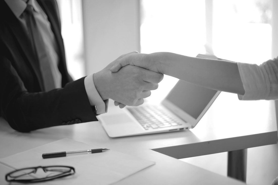 A handshake across a desk at the start of a business relationship