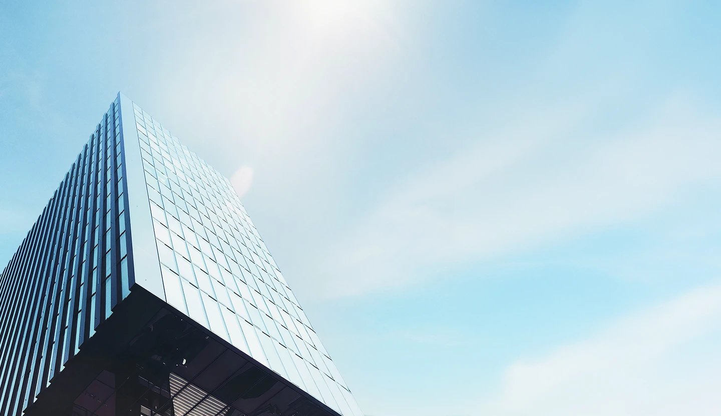 Modern glass office tower against a bright sky